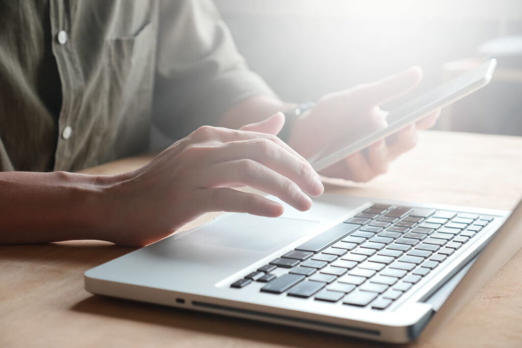 close up of male hands using laptop and tablet on the table, ton